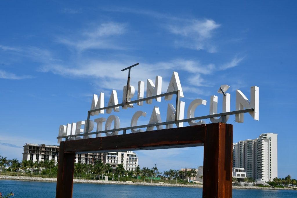 Letrero de Marina Puerto Cancún con edificios y el mar
